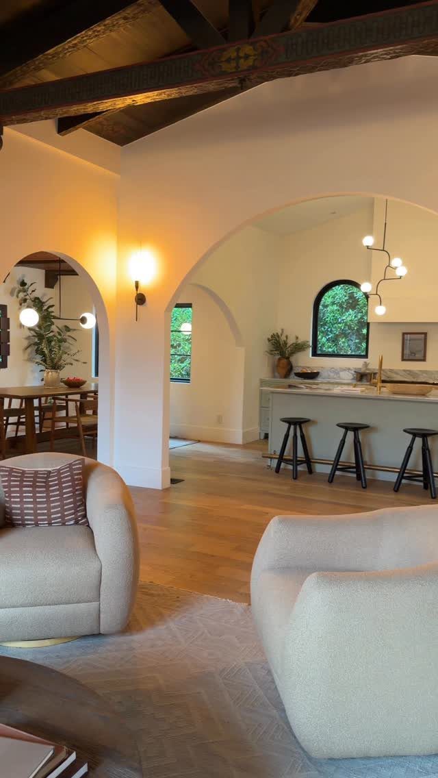 Kitchen island with three black stools viewed through a white arched doorway.