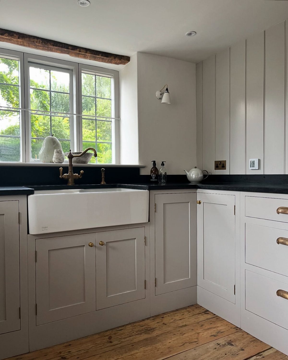 Black honed granite countertops with a white farmhouse sink and light gray cabinets.