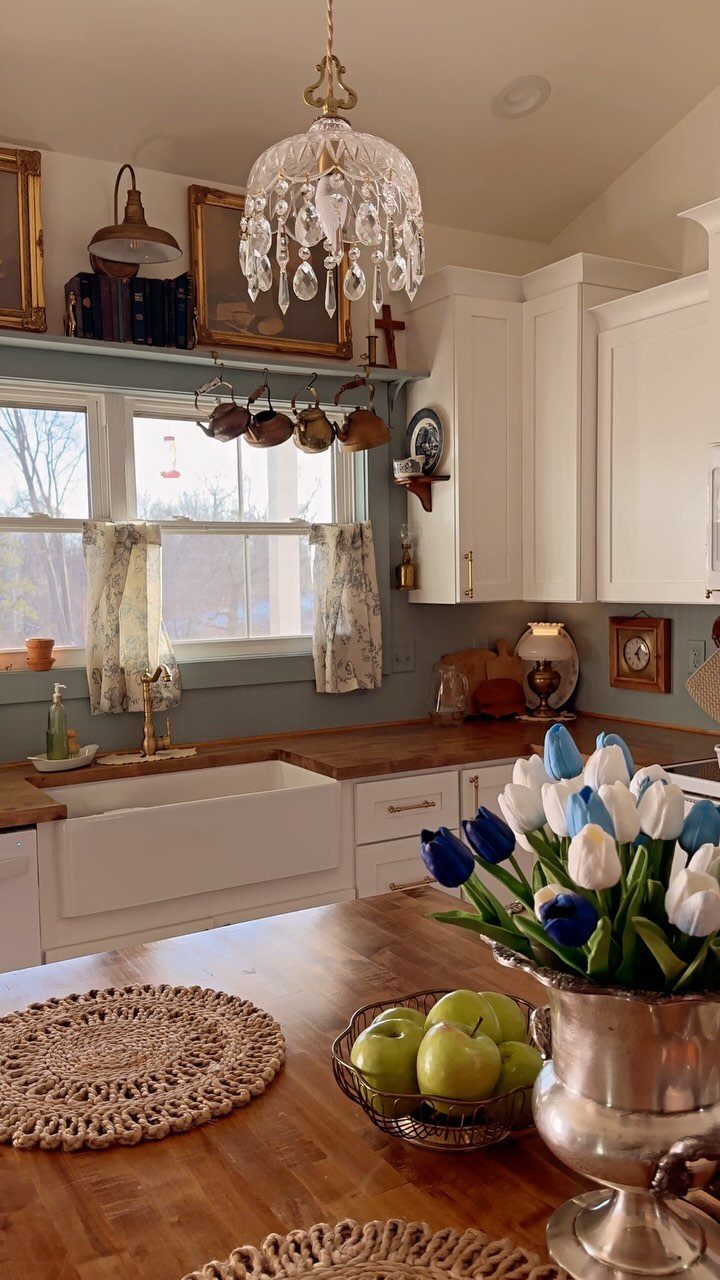 Vintage style kitchen with white cabinets, wooden countertops, and a crystal chandelier.