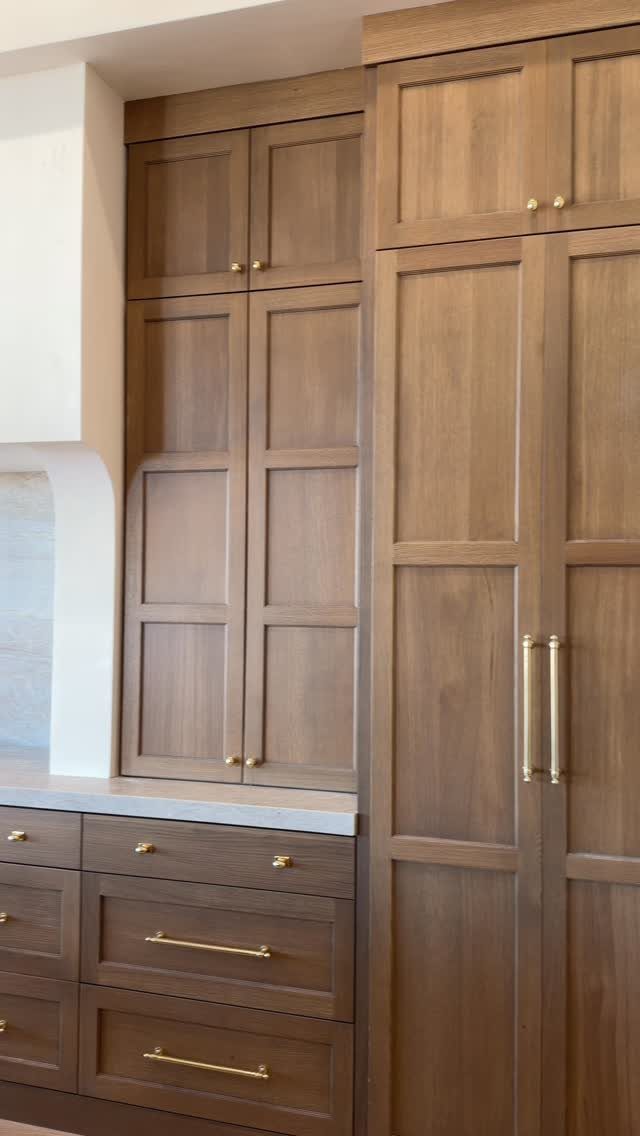 Wooden kitchen cabinets with gold hardware and a light-colored countertop in a remodel.