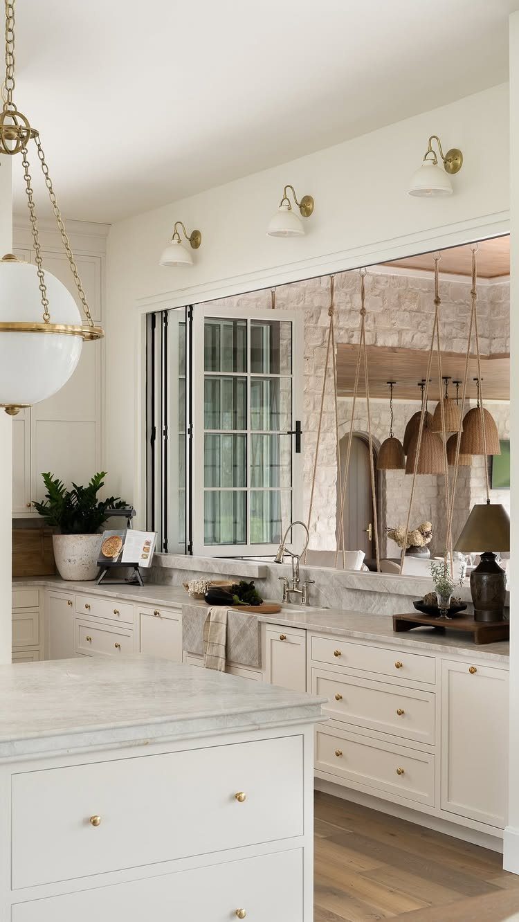 White kitchen with marble counters and a wide dining pass-through opening to another room.
