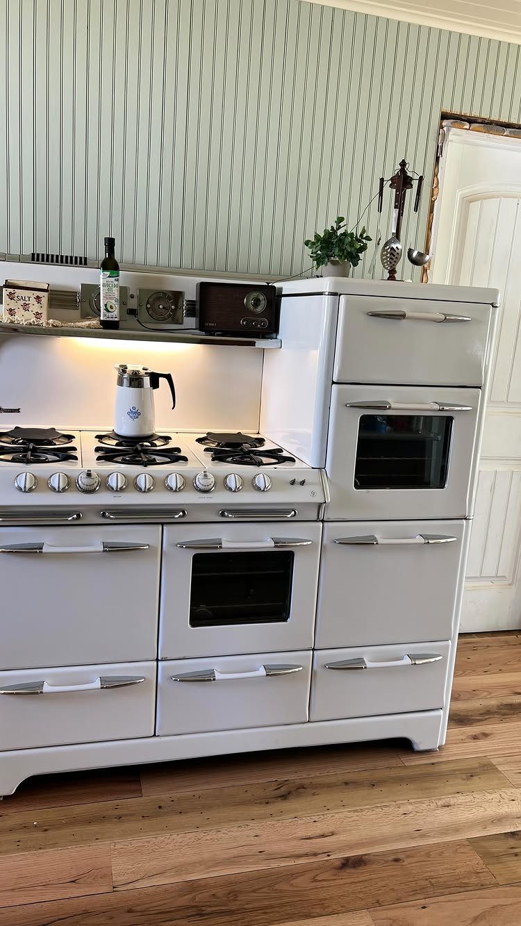 Vintage white cooking range with multiple ovens and burners in a bright kitchen