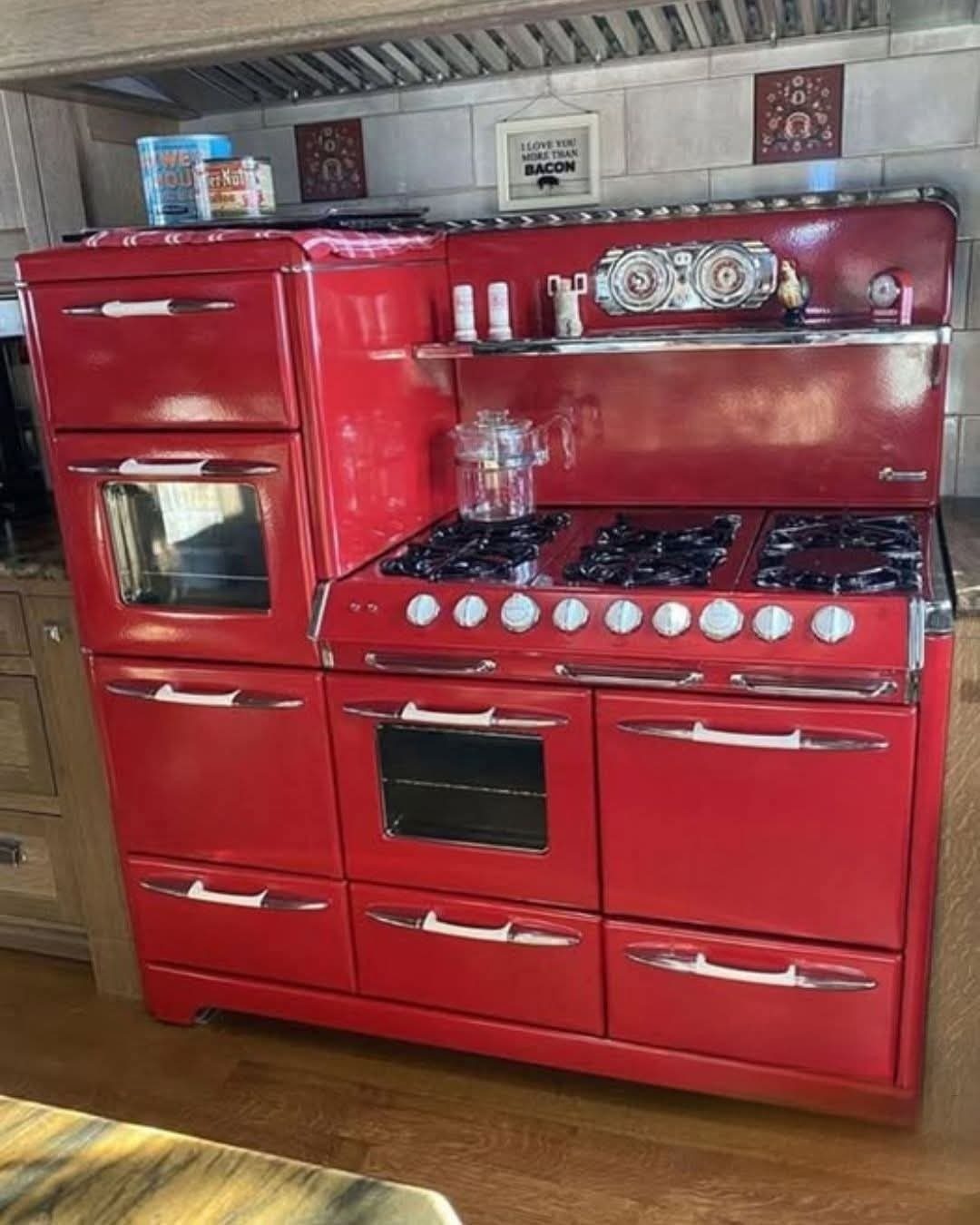 Bright red vintage-style kitchen range with chrome accents against a white tiled wall.