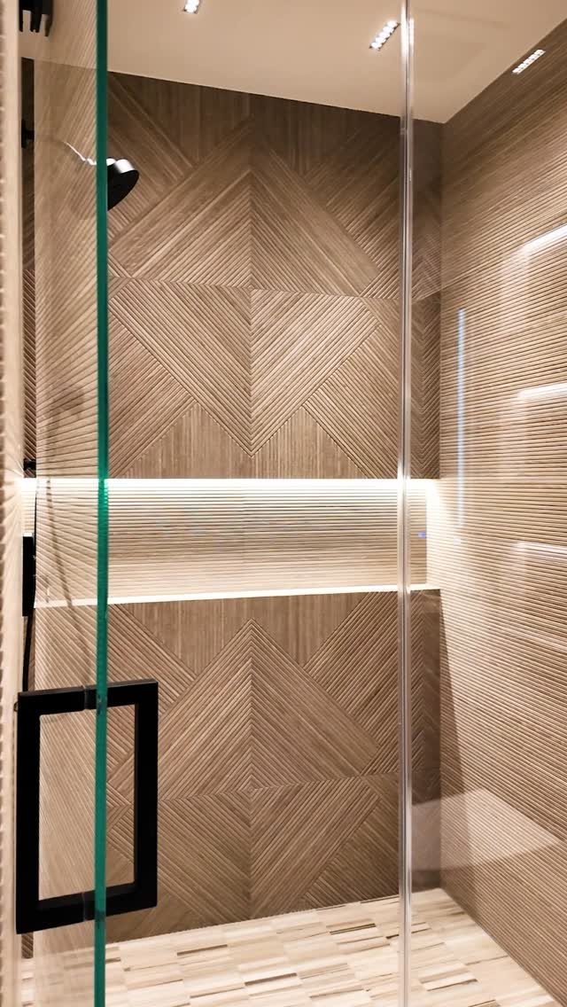 Shower with a brown textured tile accent wall in a geometric chevron pattern.