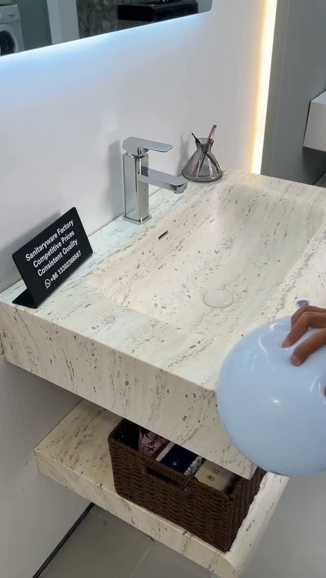 White marbled integrated sink and countertop with a chrome faucet and lower storage shelf.