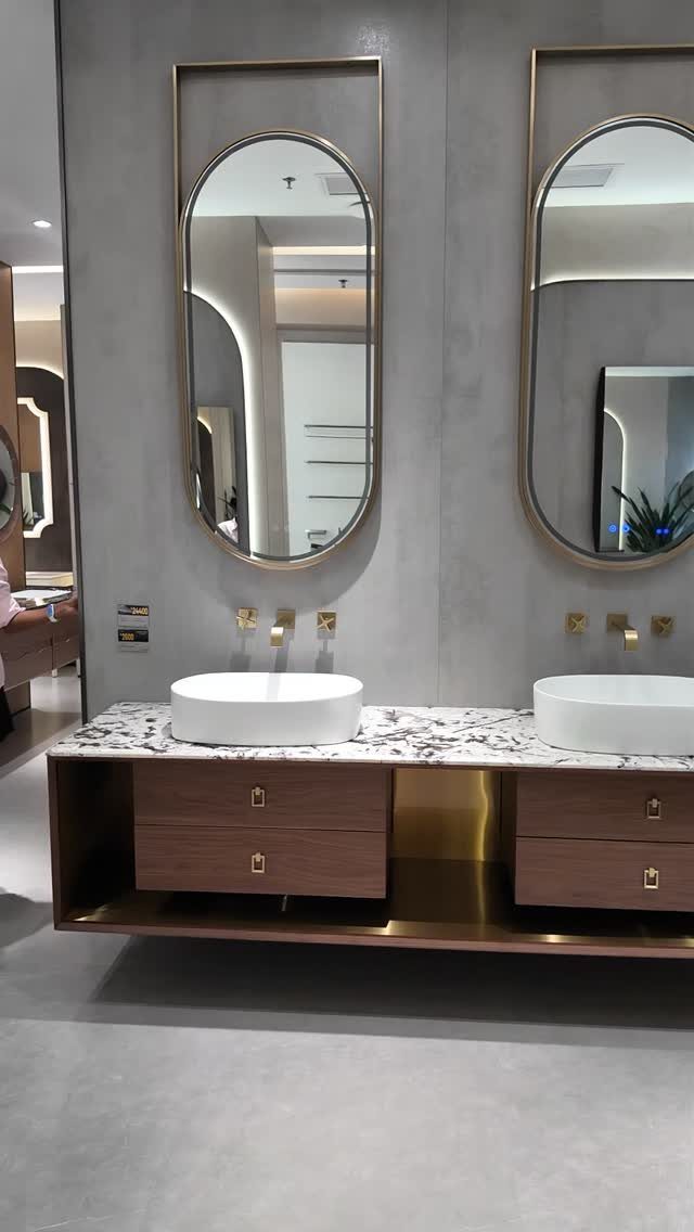 Double sink vanity with white marble top, vessel basins, and gold-framed mirrors.