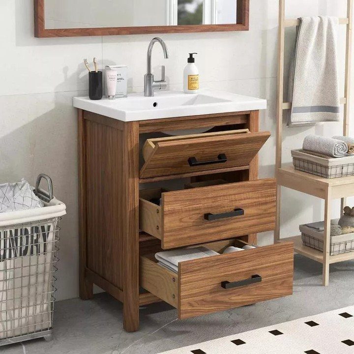 Wood-grain freestanding bathroom vanity with white integrated sink and three open drawers.
