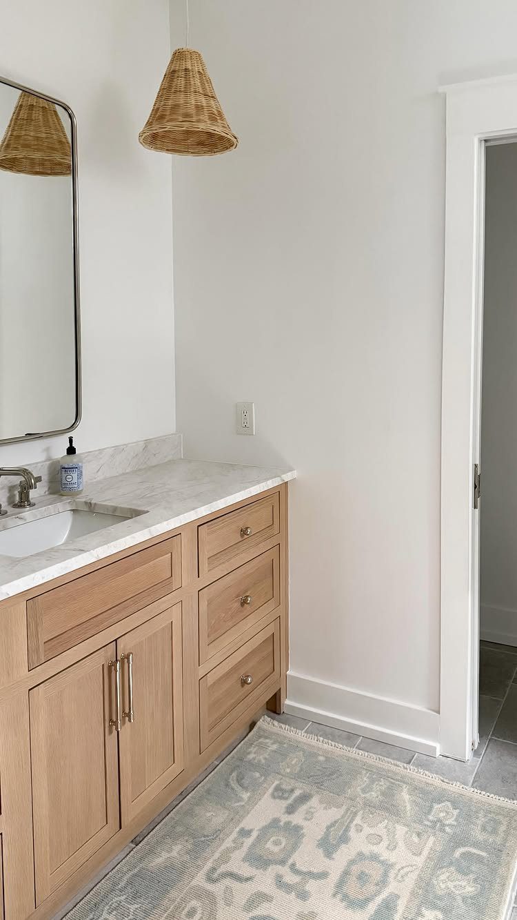 Bathroom vanity with light wood cabinets and an integrated white marble sink countertop.