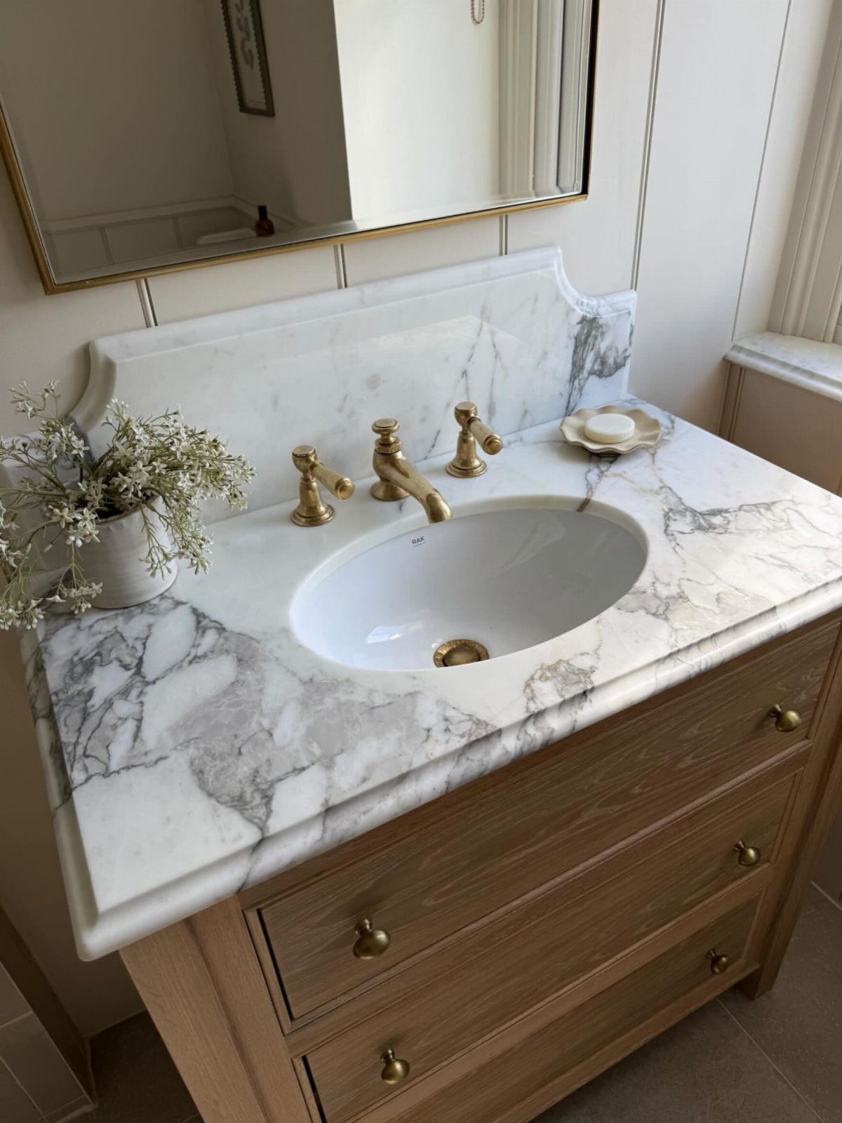 Marble-patterned bathroom vanity top with an oval sink and gold faucets.