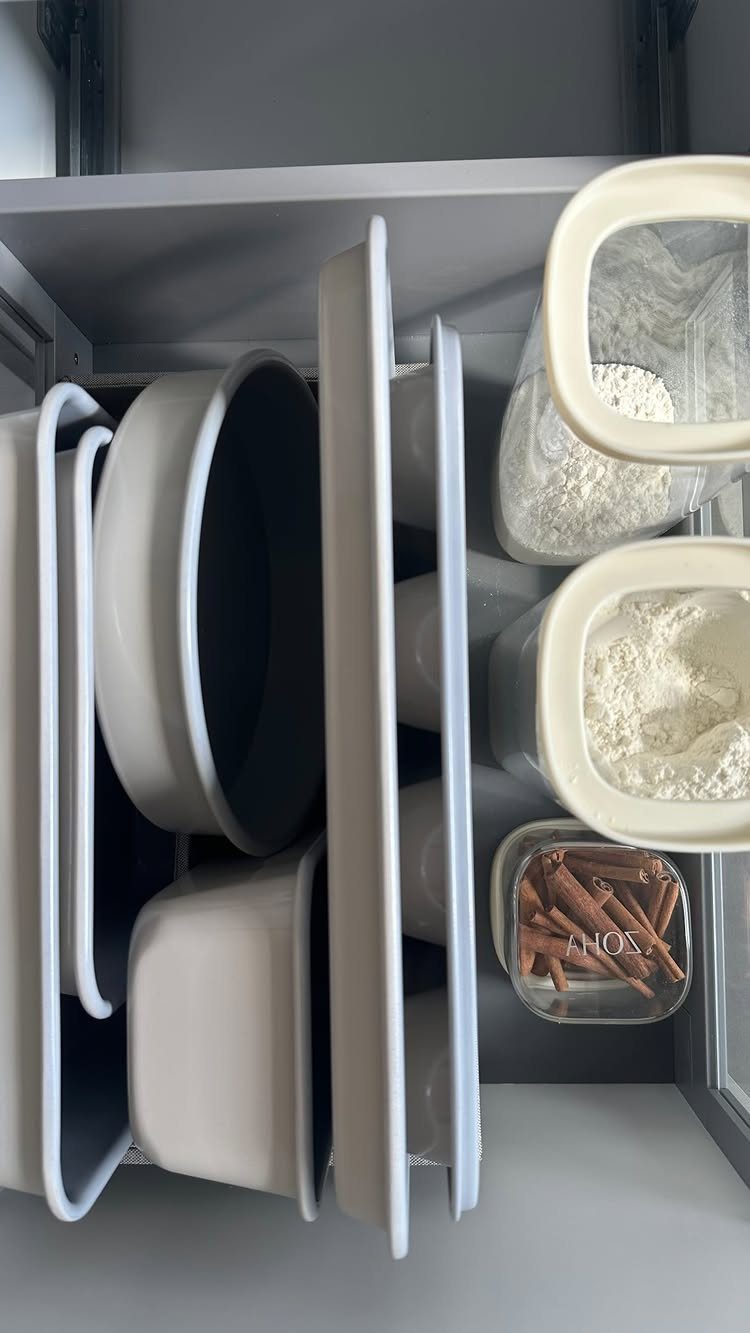 White baking pans and ingredient containers organized inside a grey kitchen drawer.