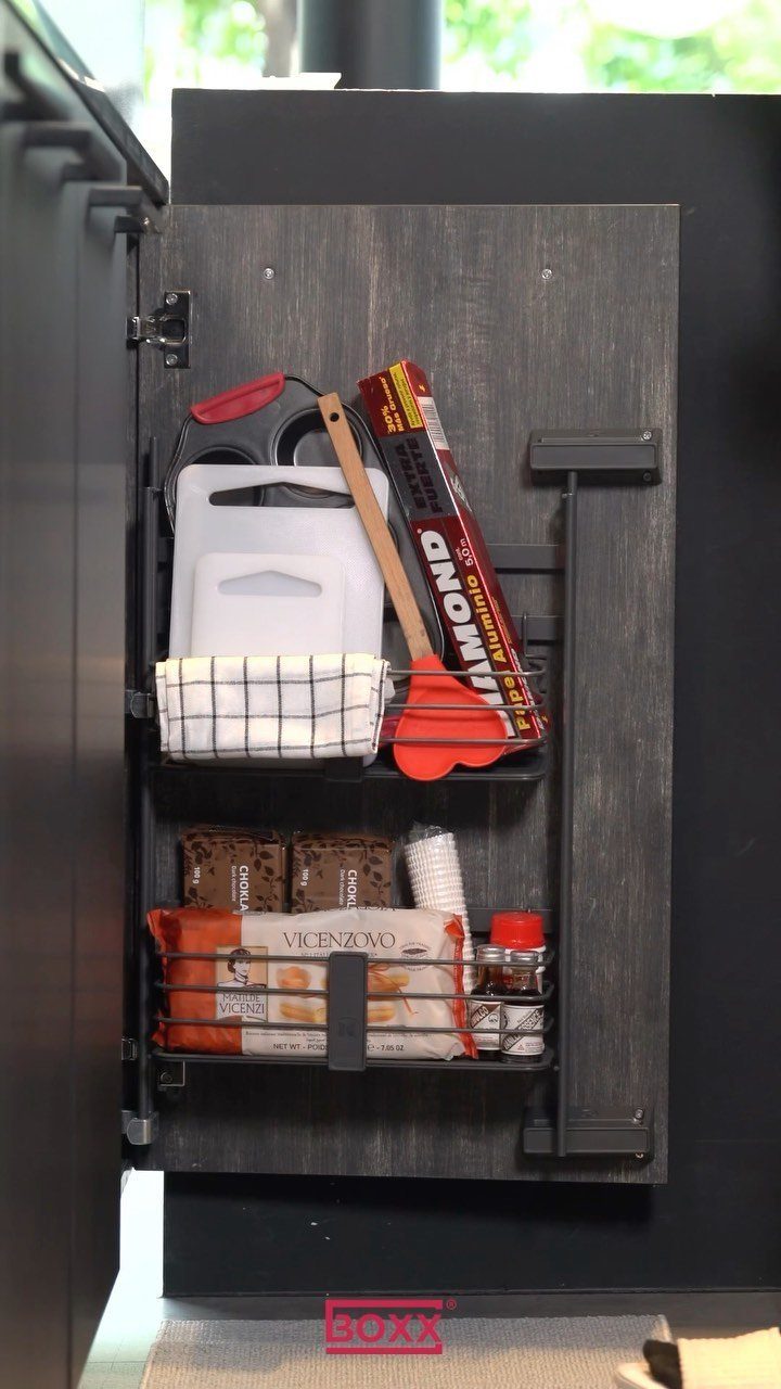 Black wire racks mounted on a dark grey cabinet door holding kitchen supplies.