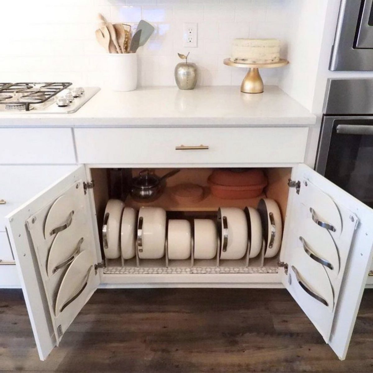 White plates stored vertically in a rack inside a lower white kitchen cabinet.