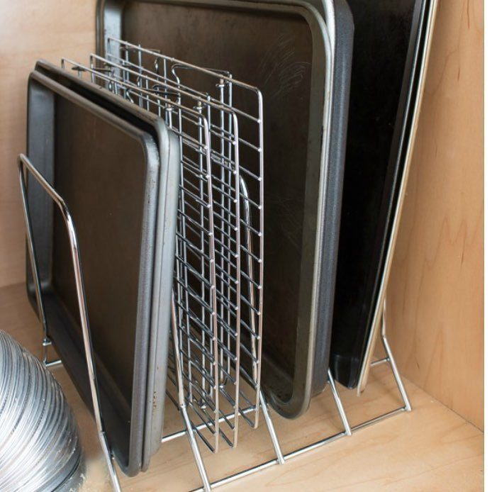 Metal wire organizer holding baking sheets and a cooling rack in a cabinet.