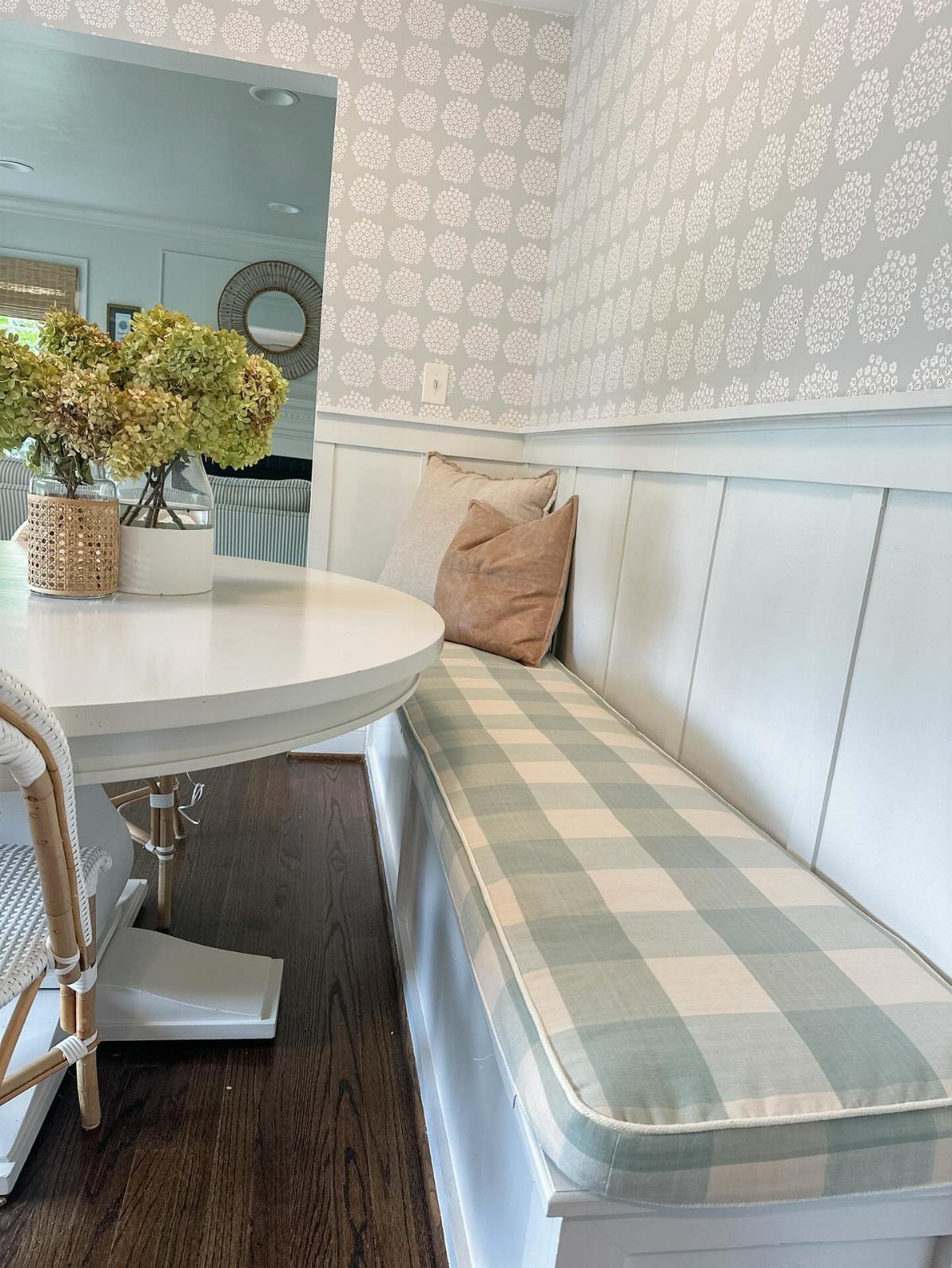 30 Banquette Dining Nook Ideas for Small Kitchens or Corners 28 White built-in banquette with a green checkered cushion and neutral throw pillows.
