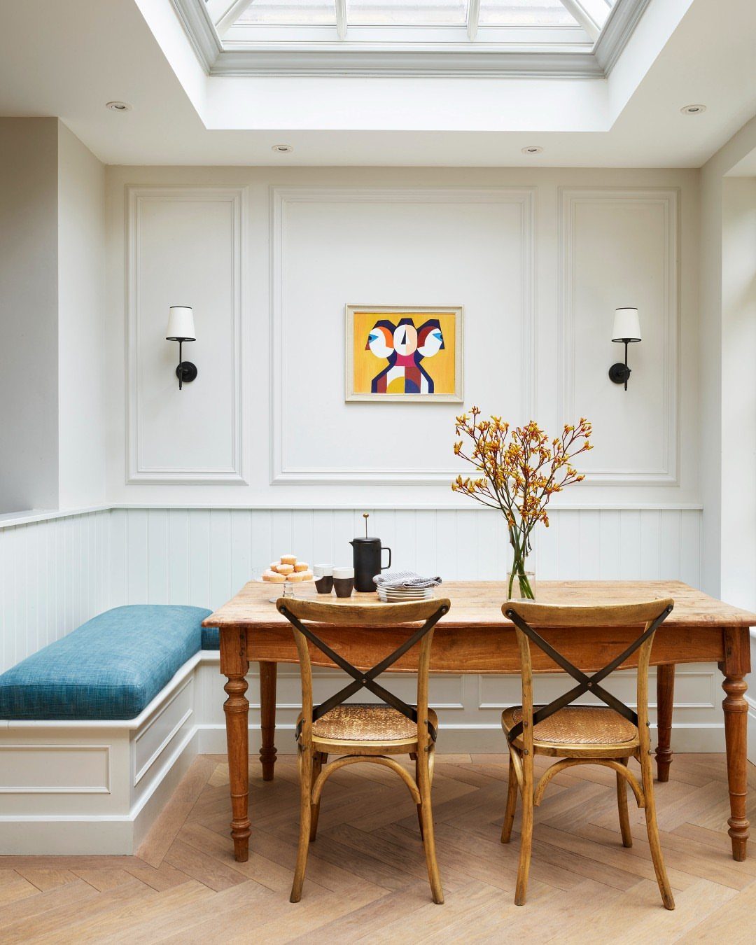 30 Banquette Dining Nook Ideas for Small Kitchens or Corners 9 Blue cushioned banquette and wooden cross-back chairs at a rustic wooden dining table.