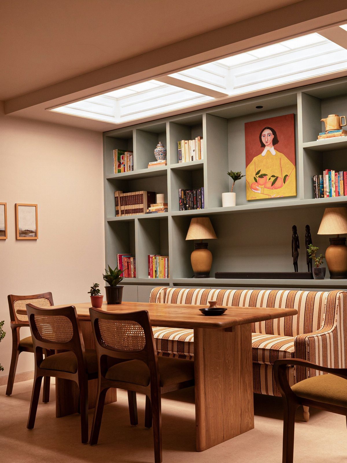 30 Banquette Dining Nook Ideas for Small Kitchens or Corners 18 Striped banquette seating in front of a grey library bookshelf with reading lamps.
