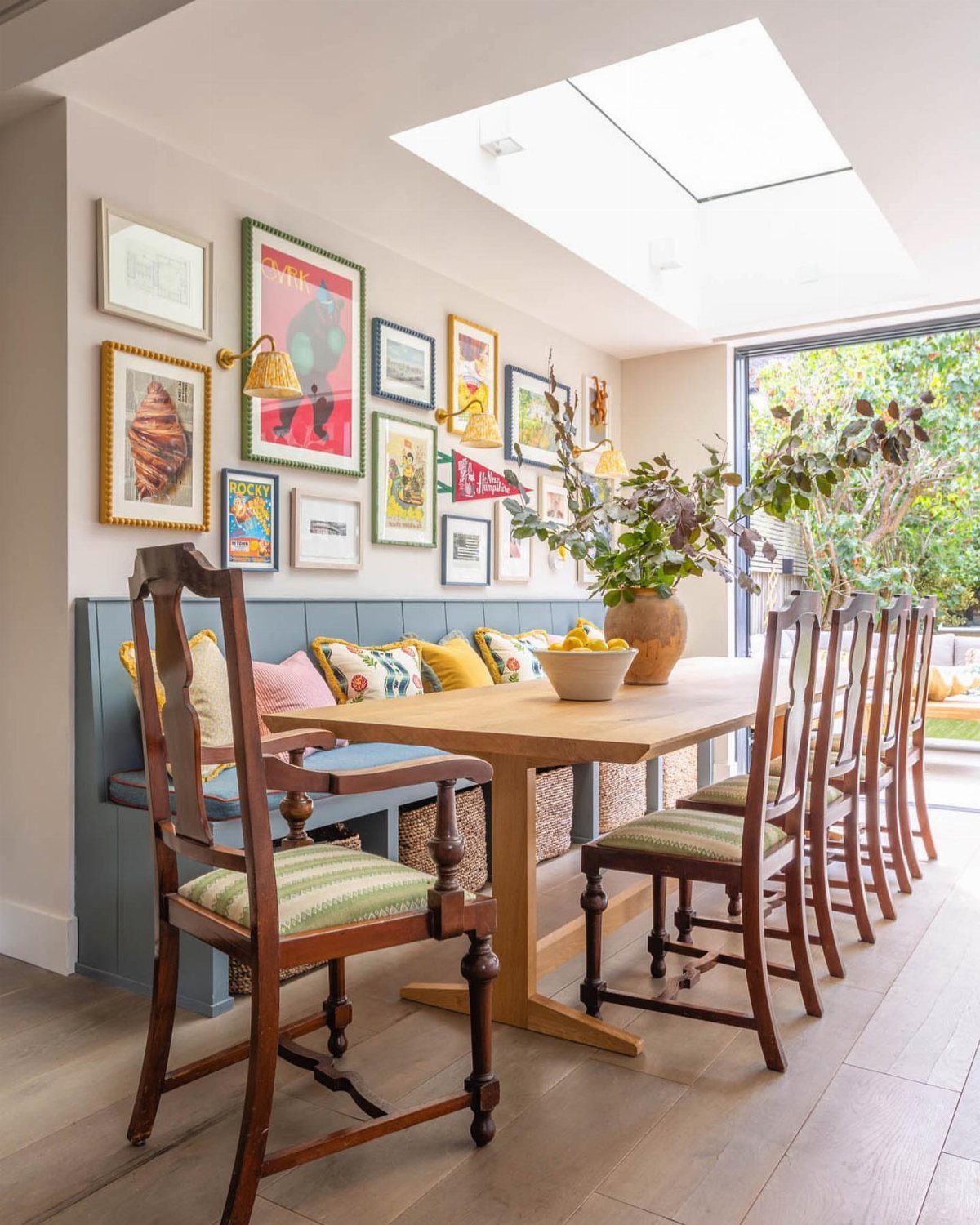 30 Banquette Dining Nook Ideas for Small Kitchens or Corners 27 Light blue banquette seating with colorful pillows and dark wood dining chairs.