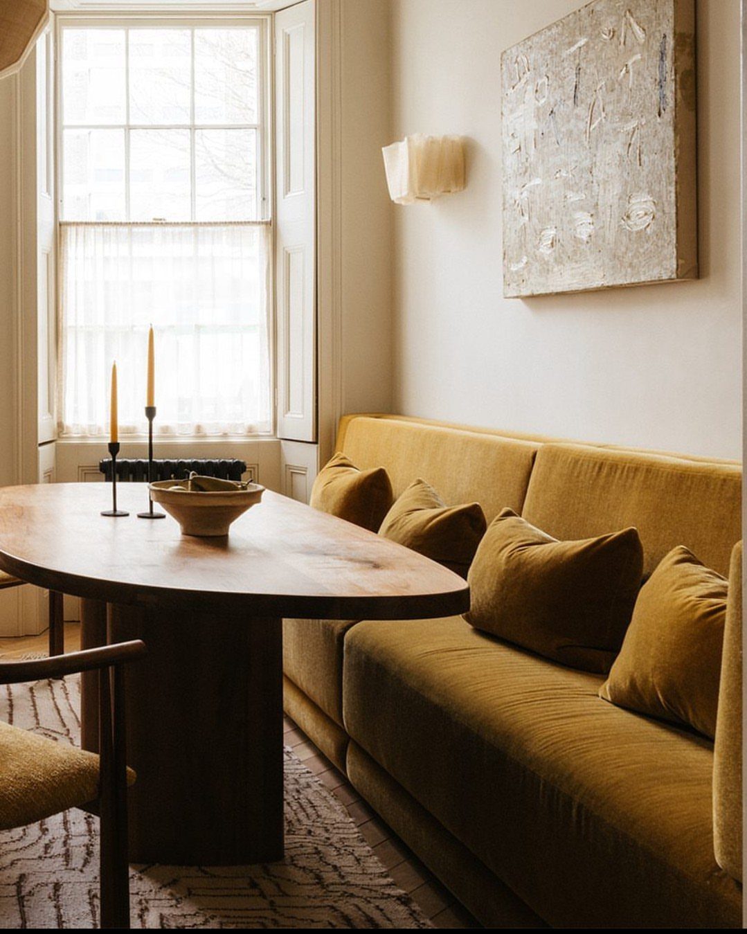 30 Banquette Dining Nook Ideas for Small Kitchens or Corners 15 Mustard yellow upholstered banquette seating paired with a dark wood raw-edge dining table.