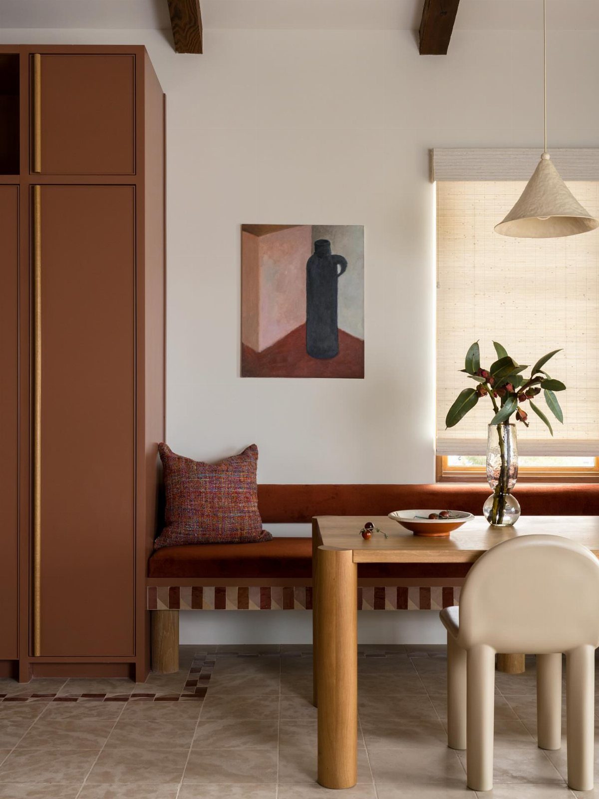 30 Banquette Dining Nook Ideas for Small Kitchens or Corners 12 Rust-colored upholstered banquette with a light wood table and a tall matching cabinet.