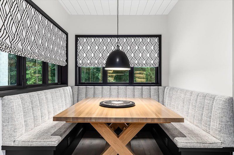 30 Banquette Dining Nook Ideas for Small Kitchens or Corners 26 U-shaped grey textured banquette with a wooden table and geometric patterned window shades.