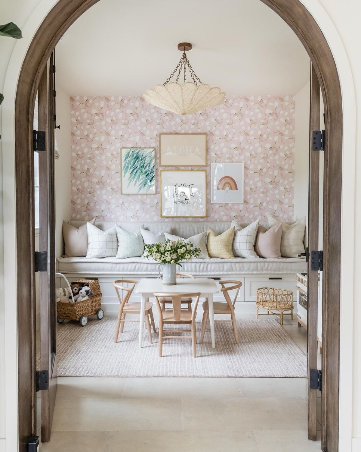 30 Banquette Dining Nook Ideas for Small Kitchens or Corners 29 White built-in banquette with pastel pillows and pink floral wallpaper in a dining nook.