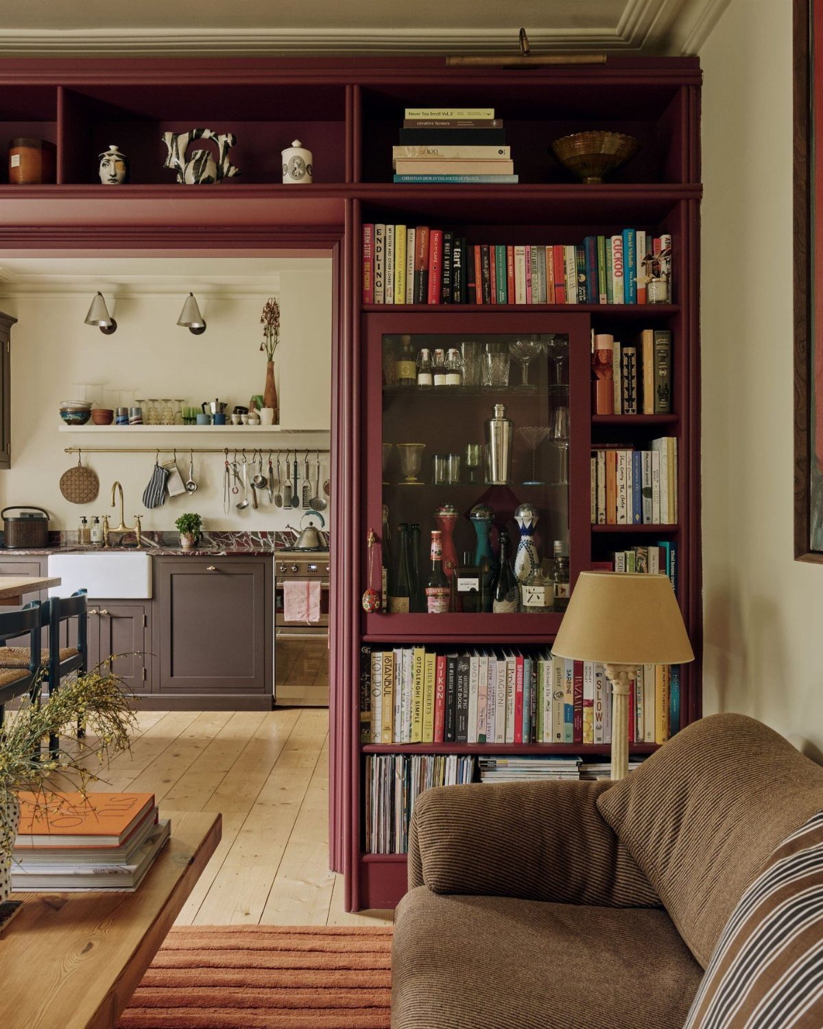 Burgundy built-in bookshelf with a glass cabinet containing liquor bottles and cocktail shakers.
