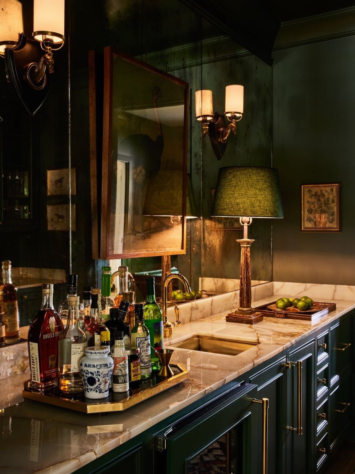 Dark green home bar with white marble counters and elegant brass hardware details.