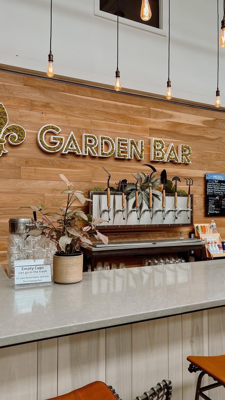 Modern indoor bar with gold Garden Bar lettering, beer taps, and Edison bulbs.