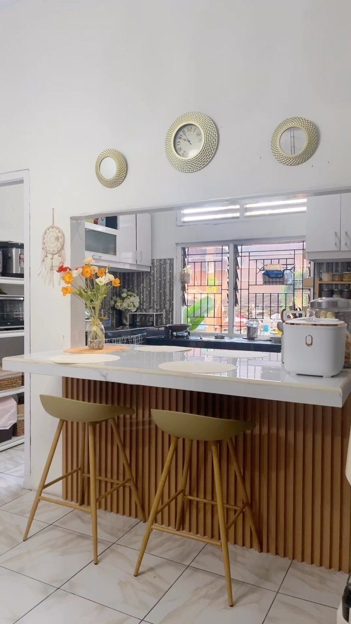 White countertop bar with fluted wood base and two tan bar stools in kitchen