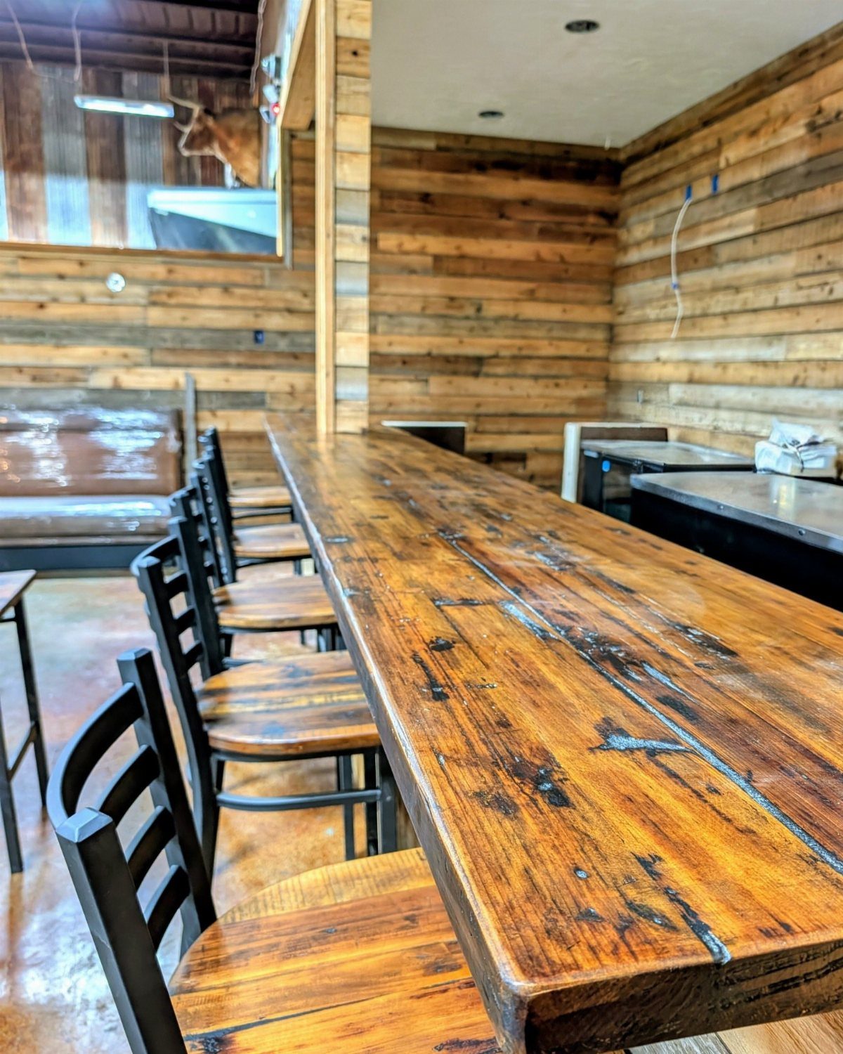 Rustic wooden bar counter with black chairs in a room with wood-paneled walls.