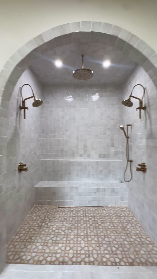 White tiled shower with an arched ceiling and a built-in tiled shower bench.