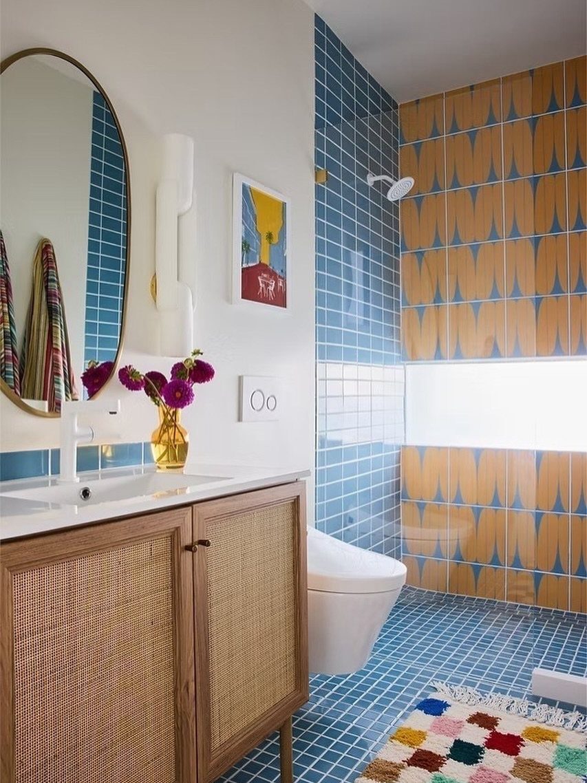 Small bathroom with blue tiles and a yellow patterned tile accent wall.