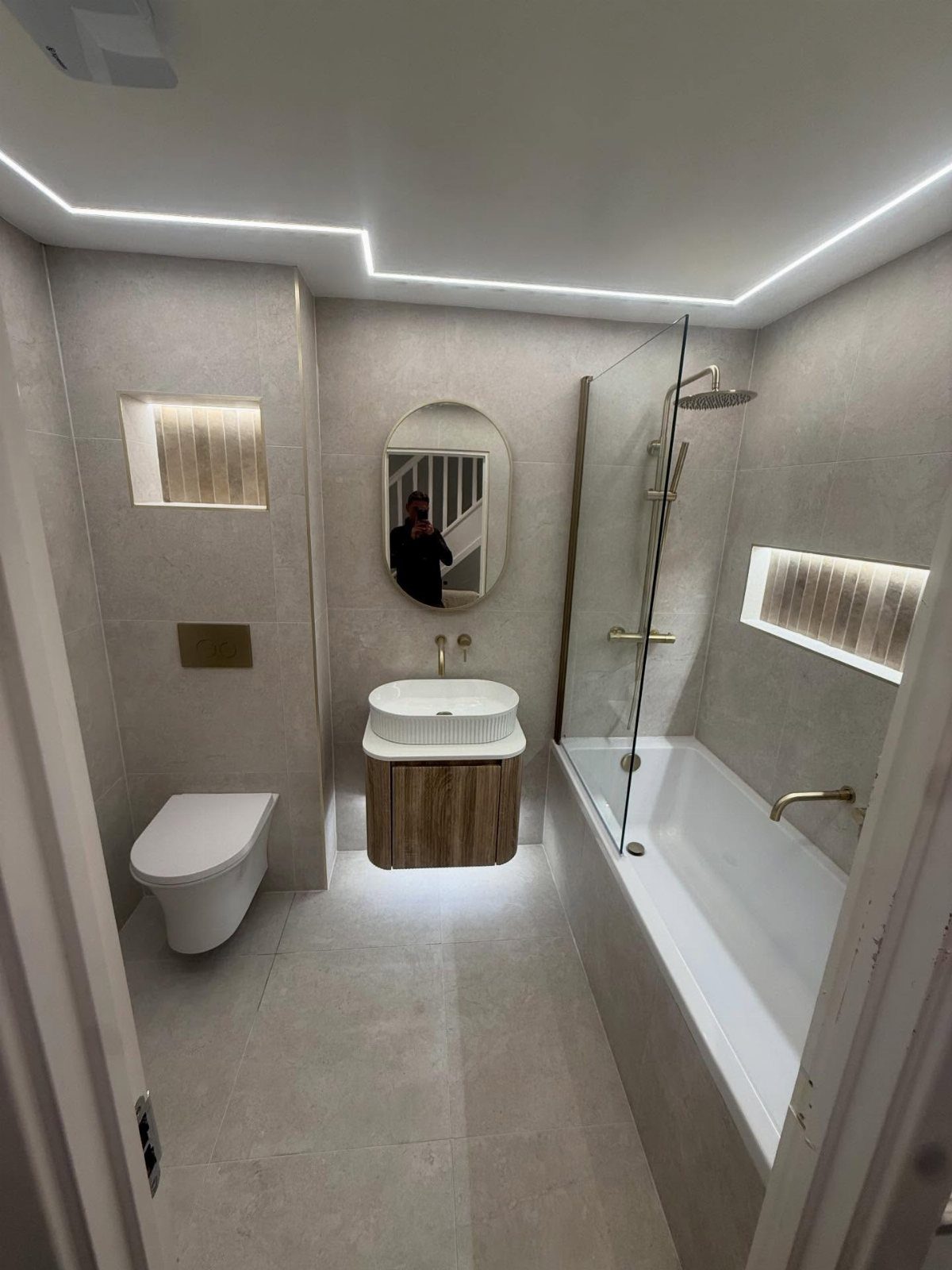 White straight bathtub with a glass shower screen in a modern grey bathroom