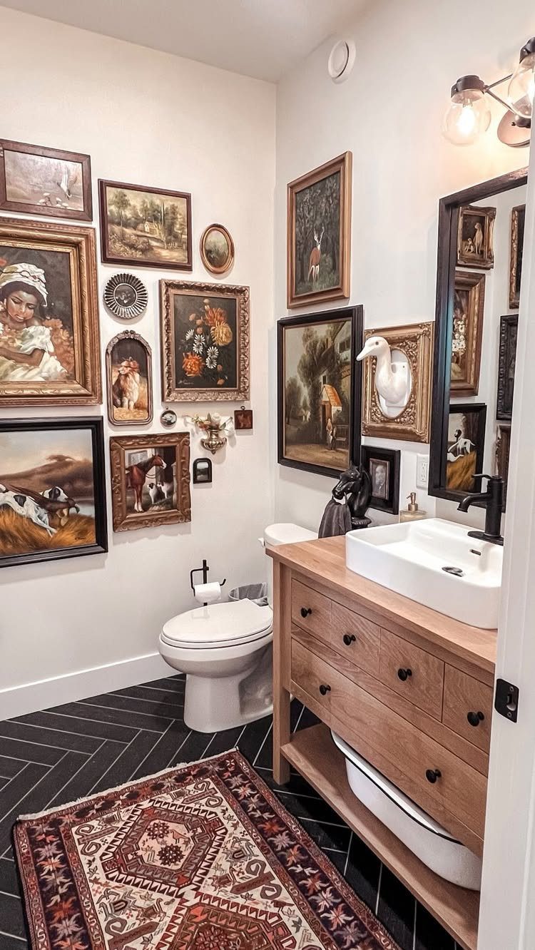 Bathroom wall decorated with a gallery of framed oil paintings above a wooden vanity.