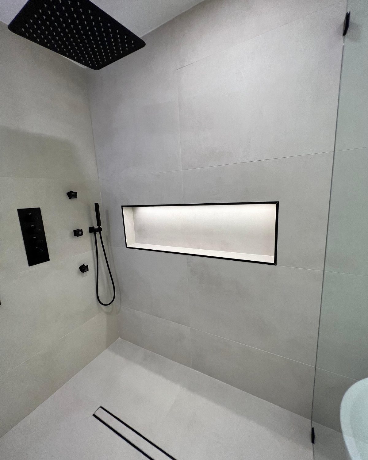 Modern white tiled shower featuring a long rectangular recessed wall storage niche.