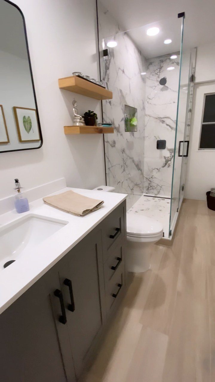 Walk-in curbless shower with white marble tiles and frameless glass in a modern bathroom