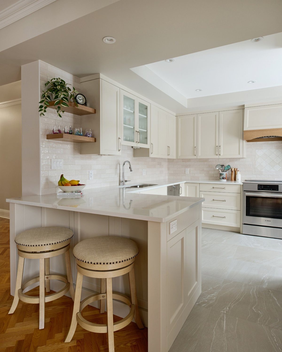 Modern condo kitchen with light cabinets, white quartz countertops, and two beige stools.