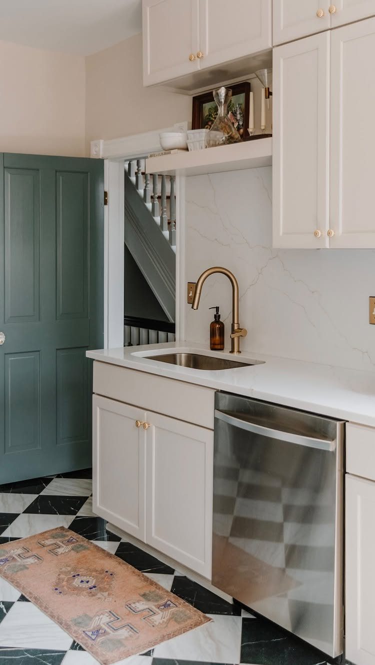 White closed kitchen cabinets and countertops with a stainless steel dishwasher and checkered floor.