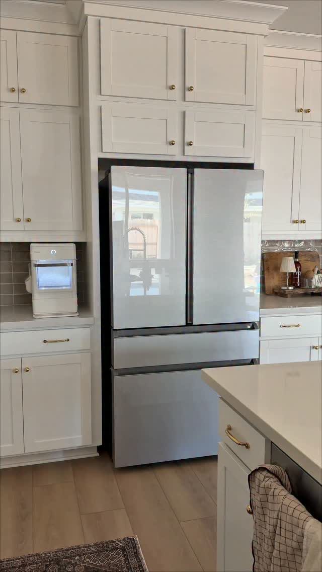 Counter-depth refrigerator integrated into white shaker cabinets in a modern kitchen setting.