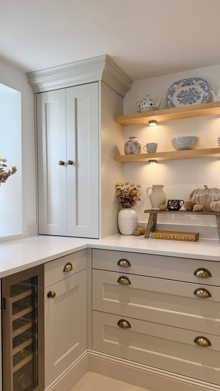 Light grey kitchen cabinets with white countertops and floating wooden shelves with integrated lighting.