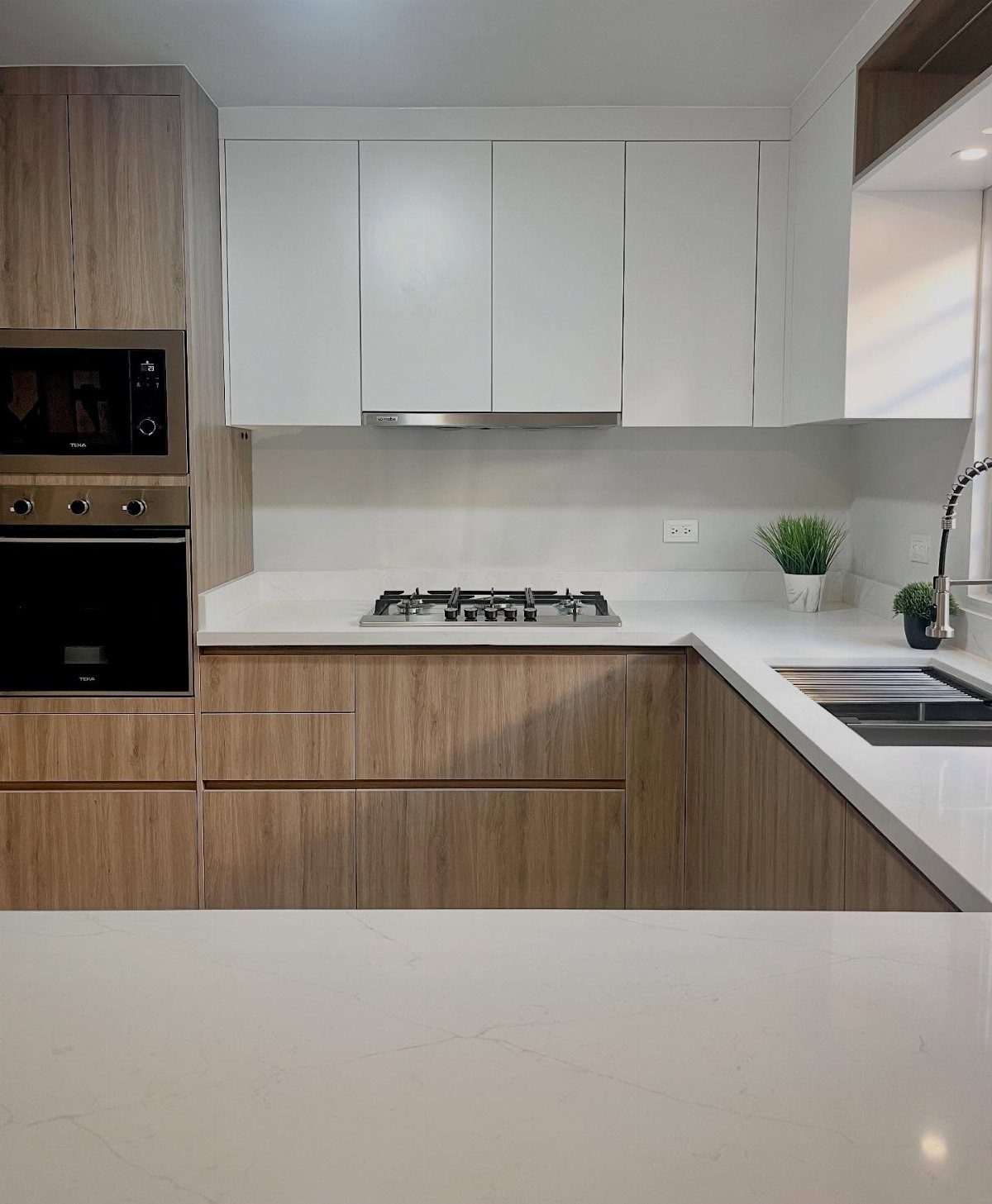 White upper cabinets and light wood lower cabinets in a modern kitchen remodel.
