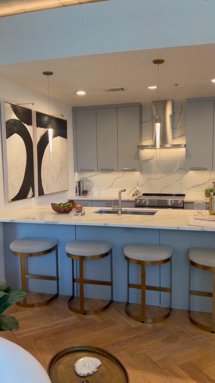 White quartz countertops with grey veining in a modern blue condo kitchen.