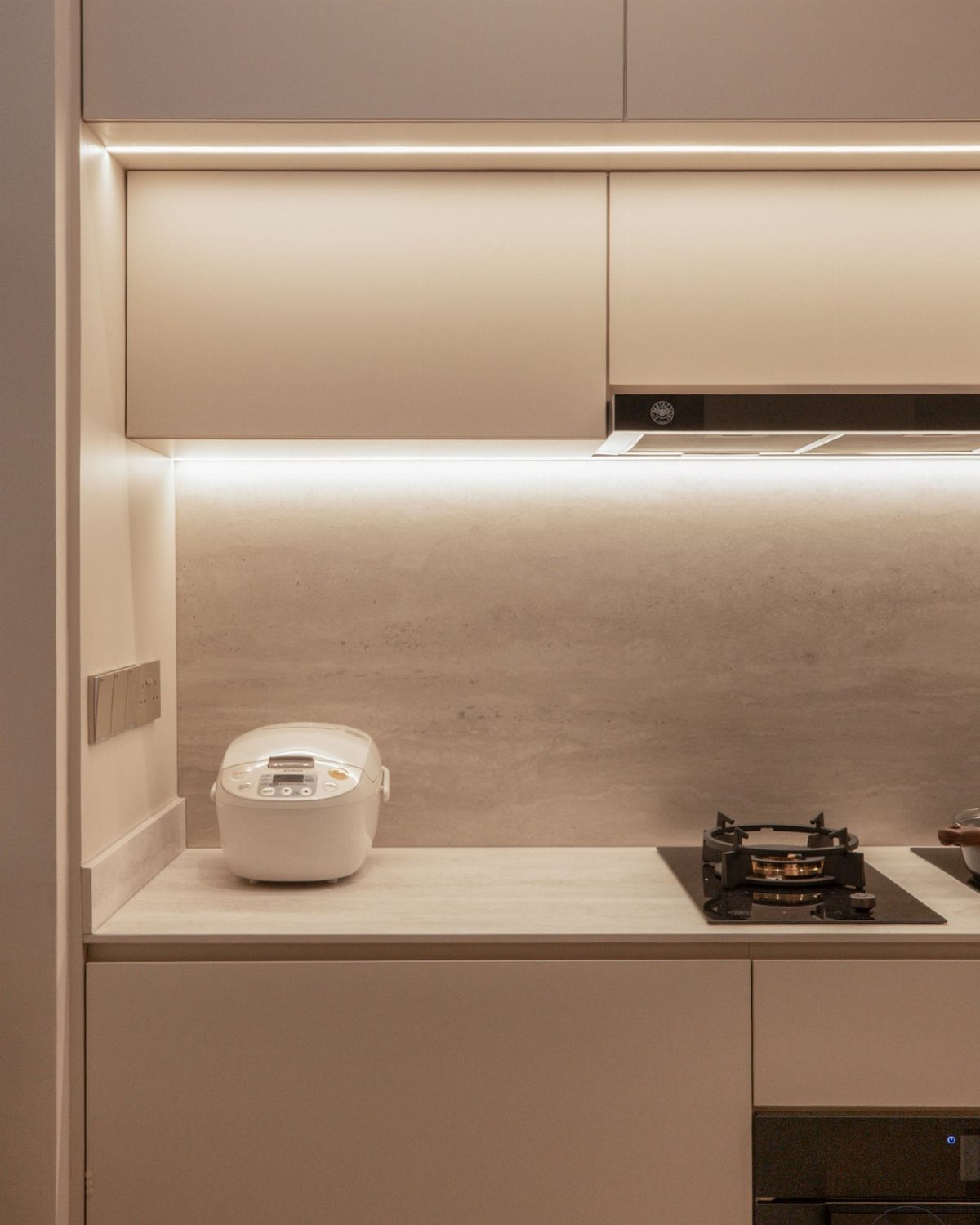 Under-cabinet LED lighting illuminating a modern kitchen countertop with a rice cooker.