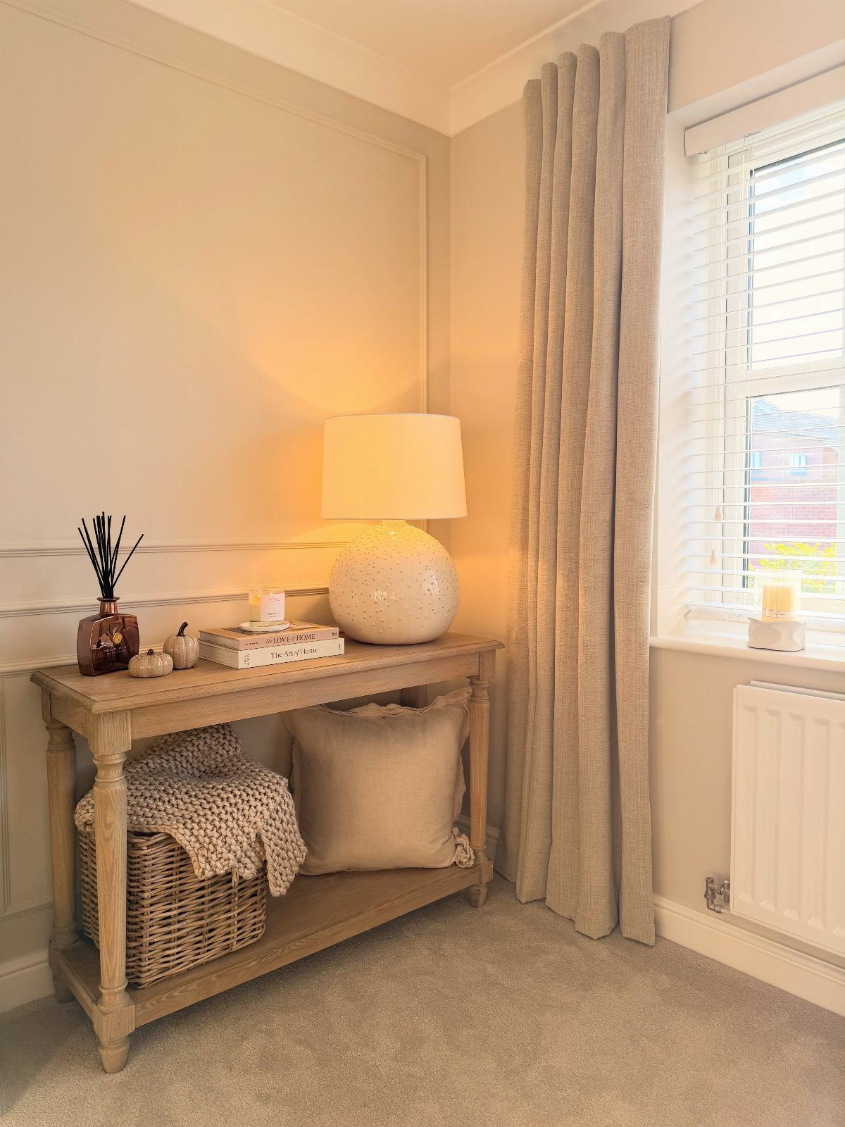 Wooden console table with a lower shelf holding a basket and a pillow.
