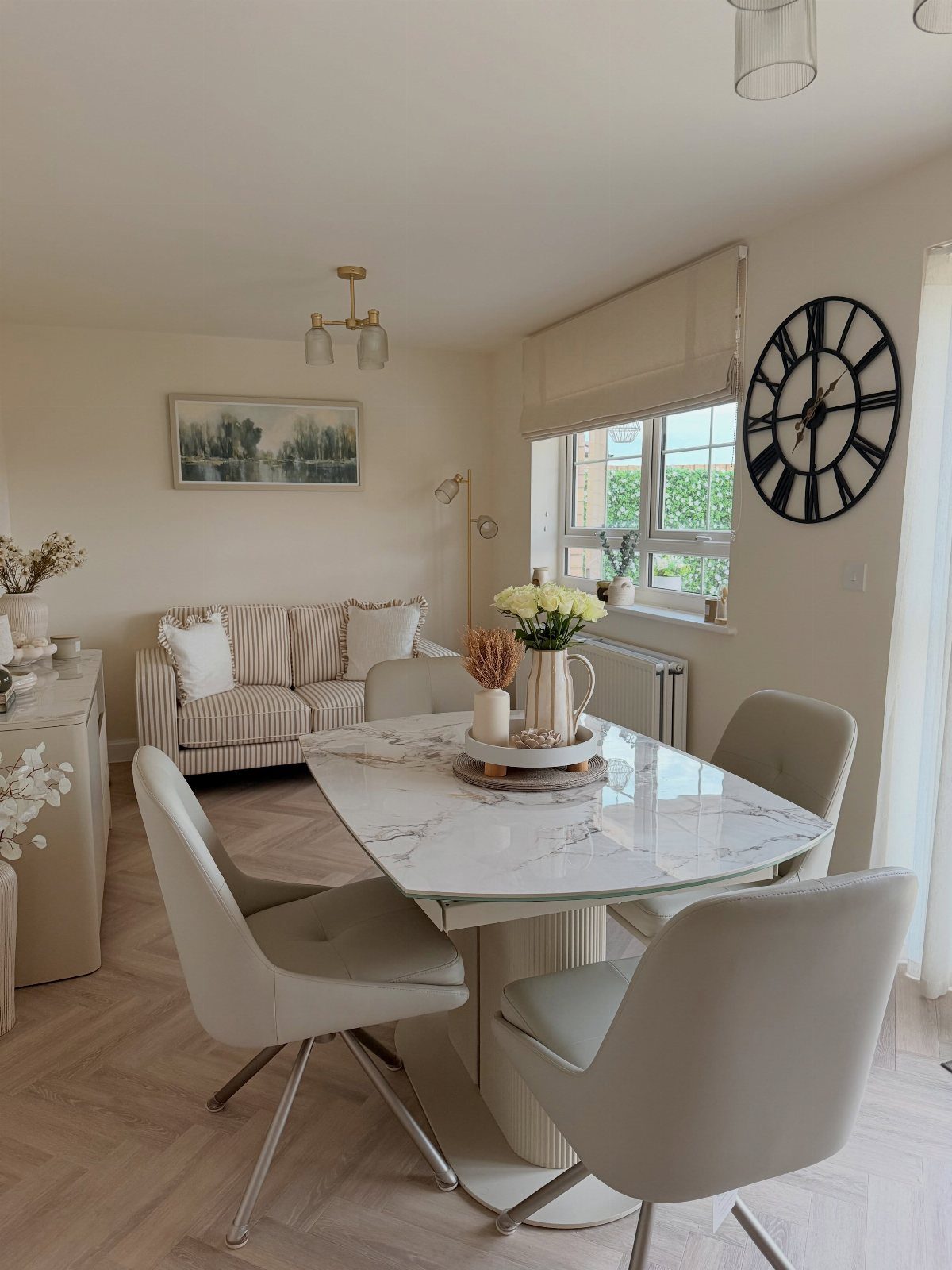 Marble dining table and beige chairs in a room with neutral-toned styling and decor.
