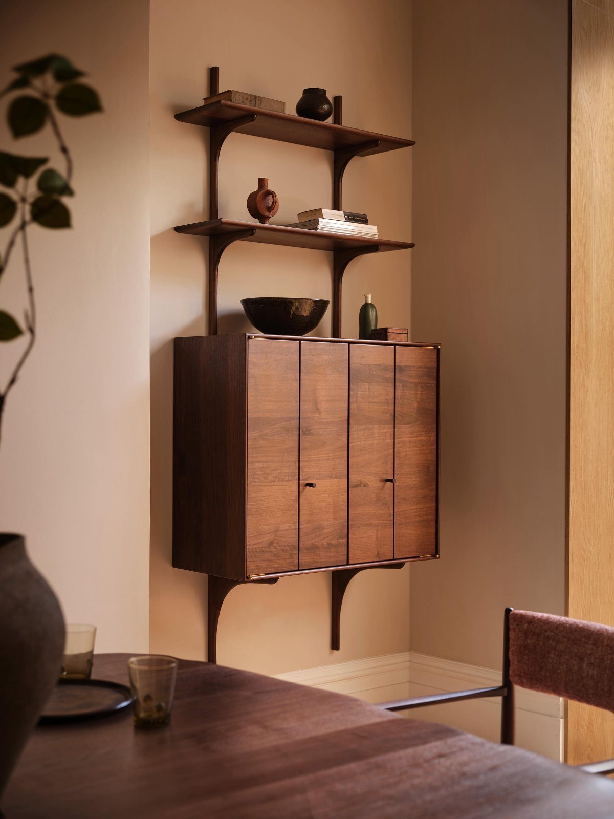 Dark wood wall-mounted cabinet and shelves decorated with minimalist vases and books.