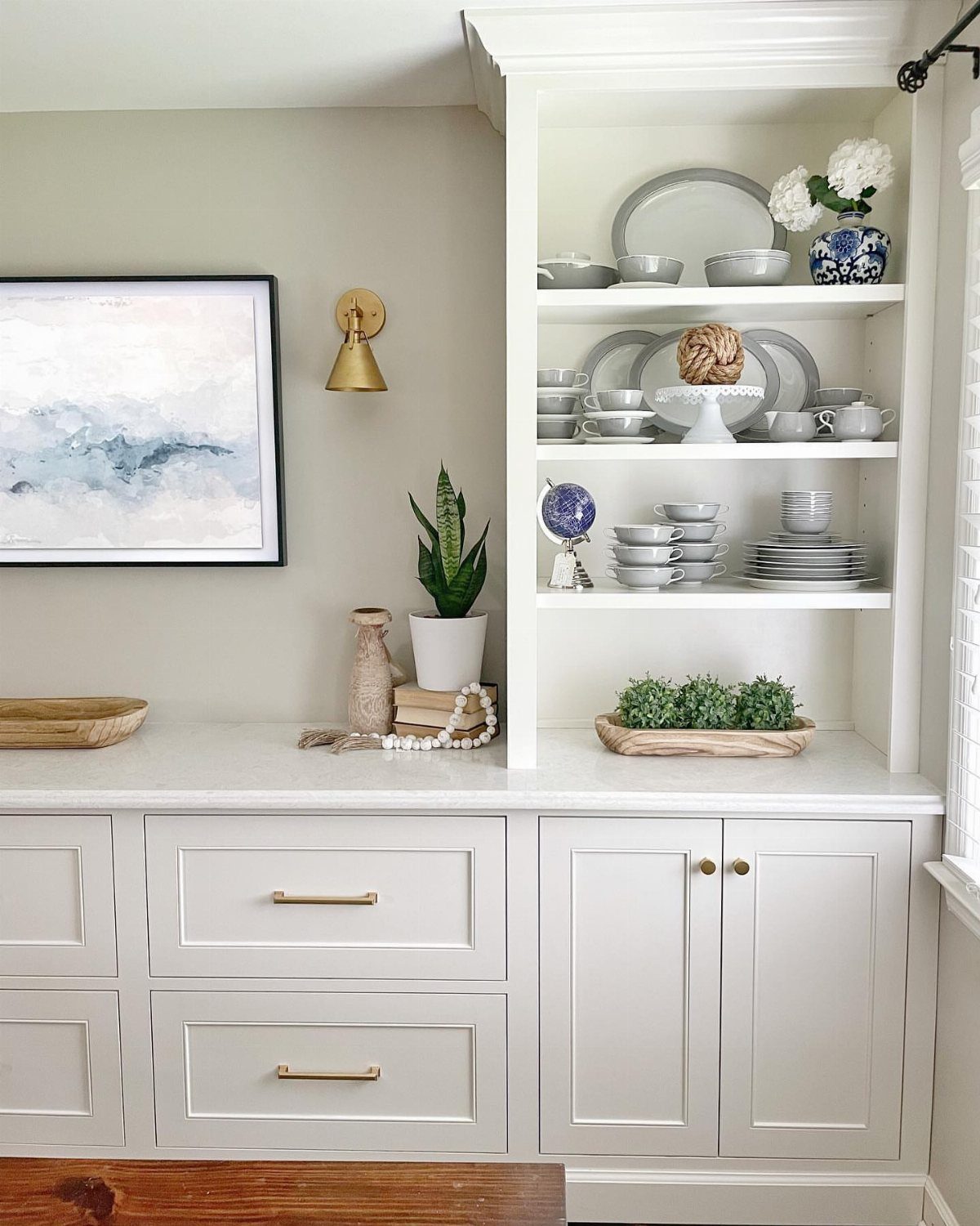 12 Dining Room Decor Hutch Ideas, From Farmhouse to Japandi 6 White built-in hutch with dinnerware and a framed abstract painting on the wall.
