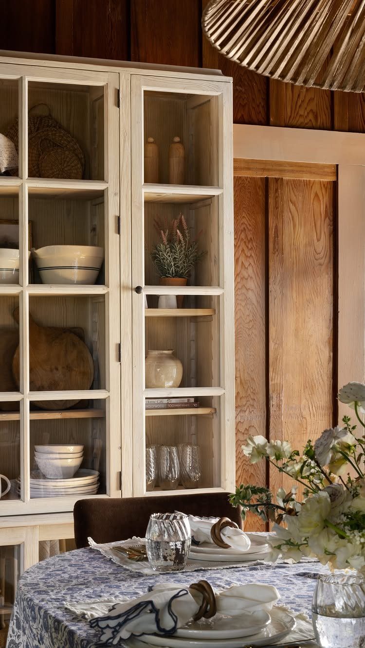 12 Dining Room Decor Hutch Ideas, From Farmhouse to Japandi 7 White glass-front hutch with neutral pottery and open shelf space in dining room
