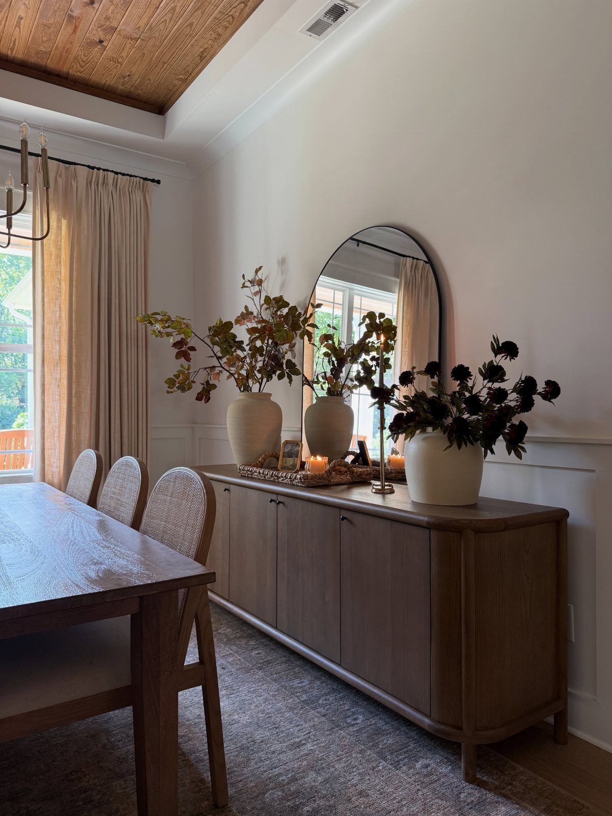 12 Dining Room Decor Hutch Ideas, From Farmhouse to Japandi 4 Wooden sideboard with three white vases of floral arrangements and a round mirror.