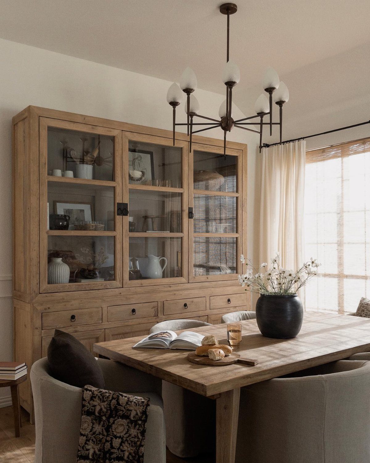 12 Dining Room Decor Hutch Ideas, From Farmhouse to Japandi 1 Light wood glass-front china cabinet filled with white pottery in a neutral dining room.